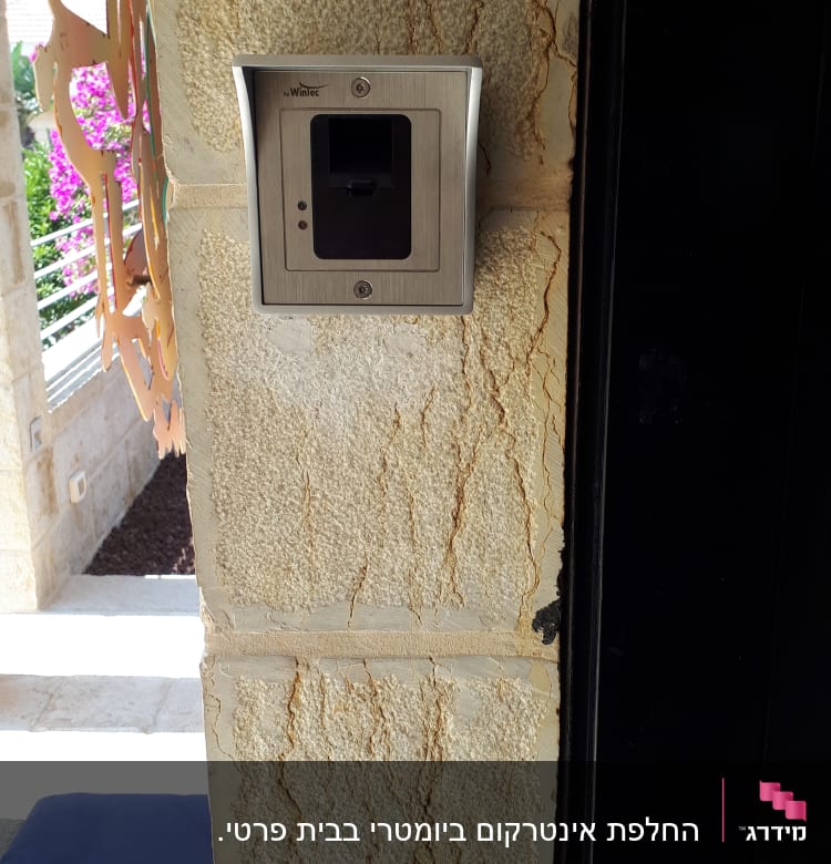 אינטרקום מתכתי מותקן על קיר אבן חיצוני